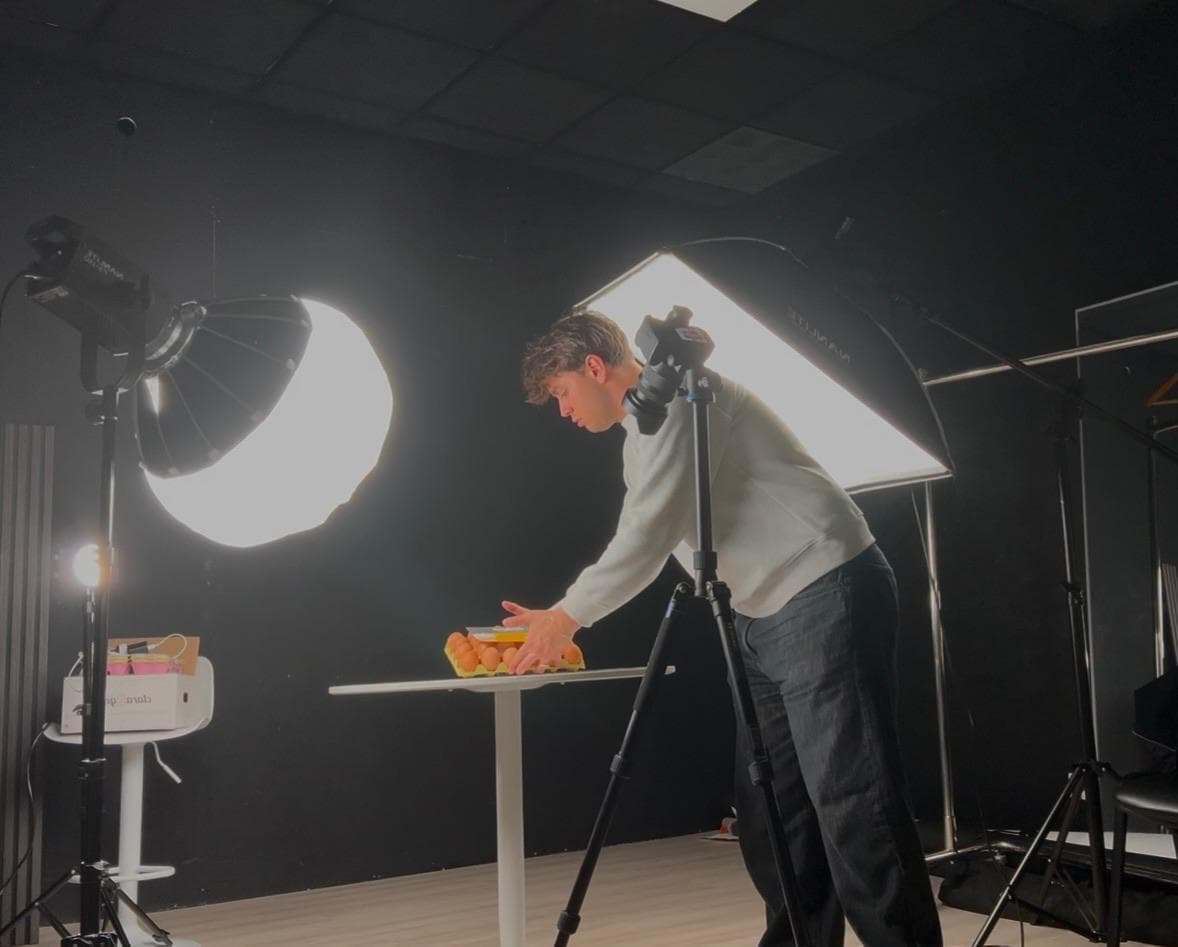 O Luis num estúdio escuro a preparar um plano de produto, com duas luzes grandes e a câmara num tripé